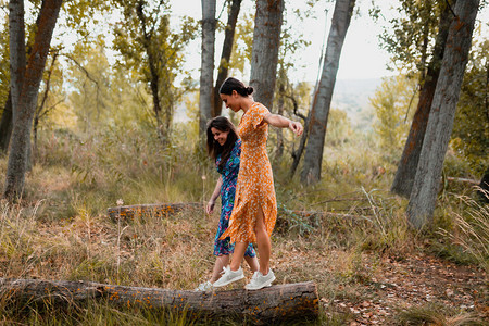 两名身穿裙子的年轻妇女在森林中行走太阳图片