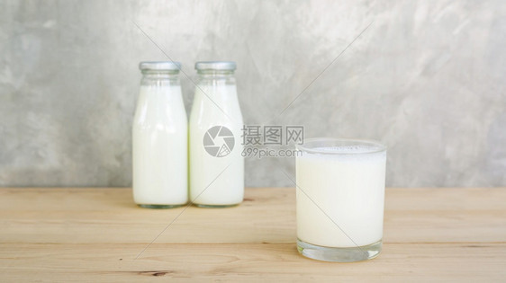 a木制桌上的奶瓶和牛杯自然产品灰色的图片
