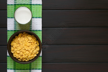 健康烤玉米片子在生锈碗里吃早餐麦片加一杯牛奶用天然光在黑木头上拍摄照片玉米花粉谷物和牛奶早餐小吃脆皮图片