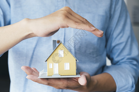 内容卖商人手握着拯救小型住房保险的屋模型以挽救小住房保险行业图片