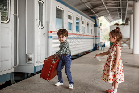 年轻的旅游肖像在小火车站穿着旧衣服和式手提箱的男女小孩和少图片