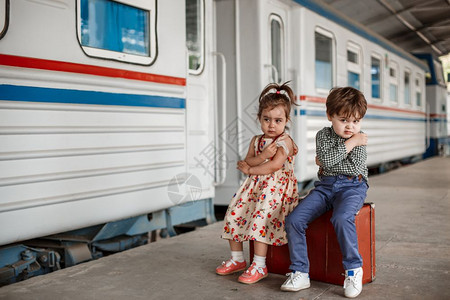 家庭孩子们情绪在小火车站穿着旧衣服和式手提箱的男女小孩和少图片