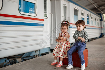 旅行男生在小火车站穿着旧衣服和式手提箱的男女小孩和少图片