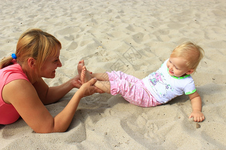 幸福婴儿衣服母亲在沙滩上玩孩子的游戏母亲在河沙上玩孩子的游戏图片