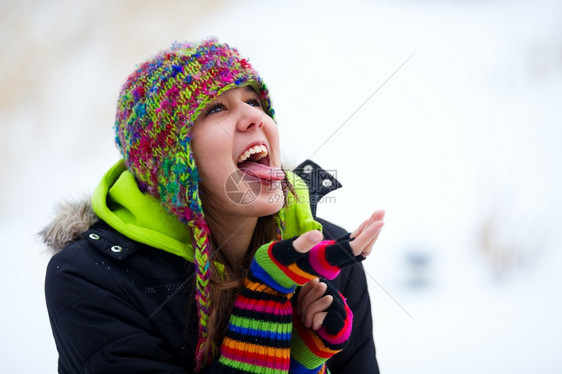 美丽的坠落一个十几岁的女孩试图捕捉落下的雪花在她舌头上肖像图片