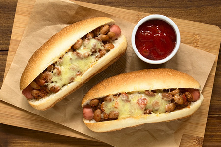 三明治烘烤的木板上配着番茄酱的烤辣热狗用自然光照在顶部木制的图片