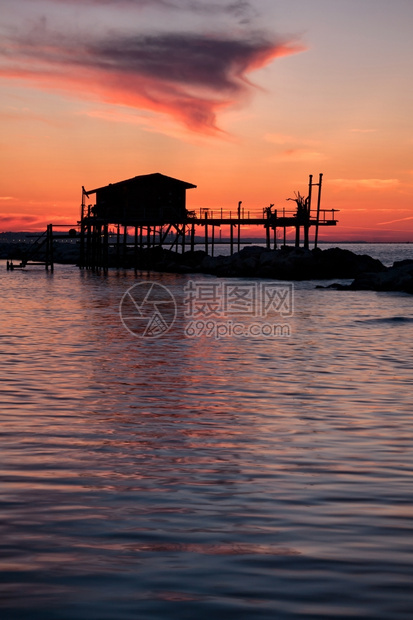 水云岩石在海面上的双影中在一个美丽的红日落漂亮灰色房子在海面双光月下图片