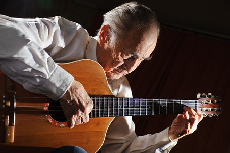 艺术家一个穿白衬衫的老人弹着声音吉他黑暗背景老的活动图片