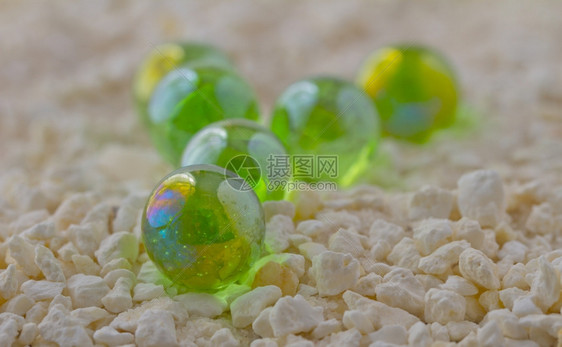 球老的白沙和小石头上的绿色玻璃弹珠白的图片