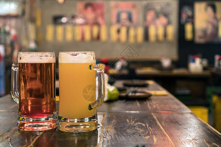 轻敲饮料工艺两杯啤酒放在吧的木桌边餐厅休息和喝酒的概念中两杯啤酒图片
