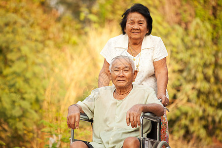 老年人推着轮椅陪丈夫在公园散步图片