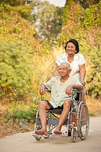 老年女性推着轮椅陪丈夫在公园散步图片