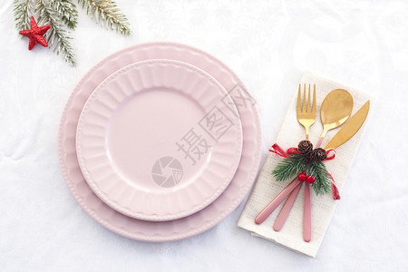 桌布圣诞餐设置两张粉红板和一色金叉子刀和一勺装饰的汤匙放在纸巾上庆典分支机构图片