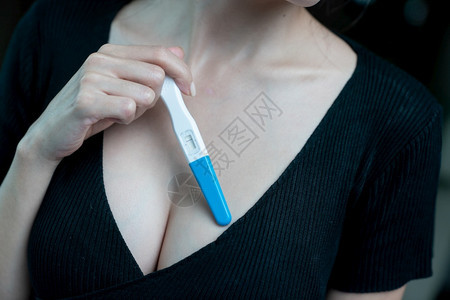 手拿验孕棒测试的女性背景图片
