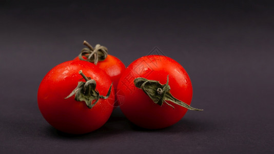 新鲜的蔬菜三樱桃西红柿在暗底背景特写上沙拉生的图片