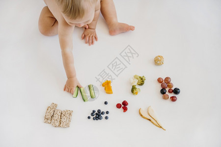 婴儿在多种食物中进行挑选图片