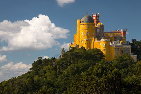 黄色的葡萄牙辛特拉佩纳宫悬崖上森林和云层环绕着辛特拉的葡萄牙Pena宫堡垒塔图片