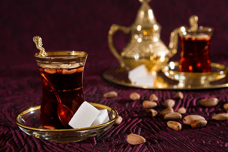 棕色的喝金传统玻璃中突尼斯茶与传统玻璃中的松子突尼斯茶特写图片