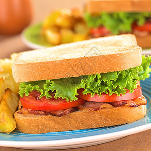 熏肉新鲜自制的BLT培生素和番茄三明治配有薯条在蓝盘上选取焦点放在三明治前面叶子盘图片