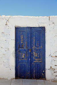 户外正面老墙壁和蓝色木门伊亚圣托里尼锡拉基克泽斯群岛爱琴海希腊欧洲老房子建筑细节伊亚欧洲门口背景图片