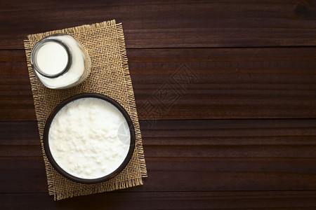 最佳高架益生菌Kefir牛奶碗中的Kefir粒子边有一瓶牛奶用自然光照着Kefir图片