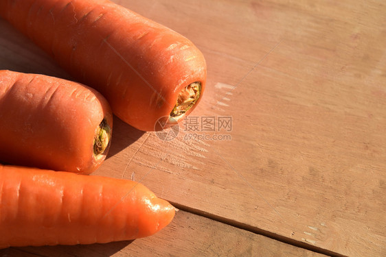 成熟新鲜的束木地板上有叶的新鲜胡萝卜图片