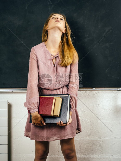 常设照片来自一位在课堂黑板前持有书籍的沮丧青年学生照片成人苦恼图片