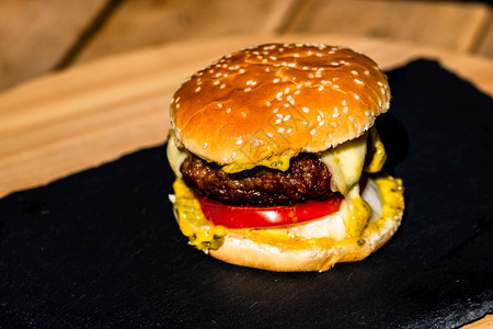 芝麻黑色背景的新鲜美味牛肉芝士汉堡和熔化乳酪详细数据传统的汉堡包图片