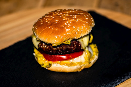 黑色背景的新鲜美味牛肉芝士汉堡和熔化乳酪详细数据番茄节美食图片