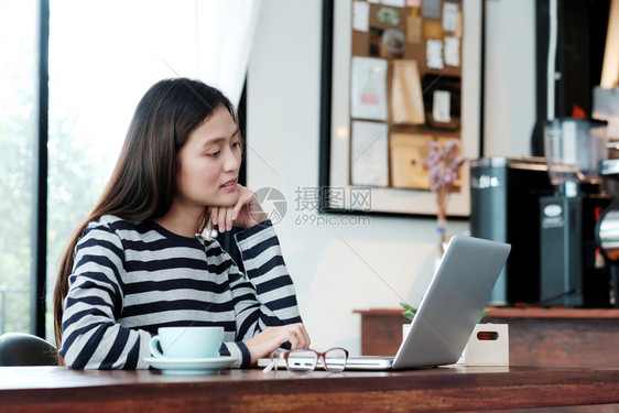 曼谷在咖啡馆使用笔记本电脑并具有复制空间人和技术生活方式的随便风格年轻女亚洲妇的现代图片
