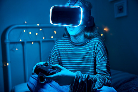 夜里穿着虚拟现实头巾的床铺女青少年在家中玩视频游戏可穿戴耳机玩家图片