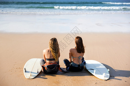 冲浪爱好者们带着冲浪板坐在沙地上图片