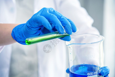 健康发现科学实验室研究员在用蓝色和绿溶液进行测试化学图片