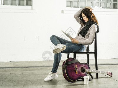 学习一种娱乐坐在椅子上写歌的美丽红发女在她旁边唱着音乐吉他图片