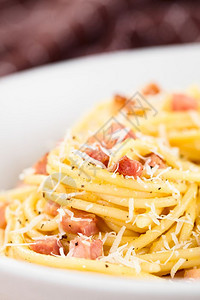 传统的意大利面粉碳酸盐SpaghettiCarbonara在非常浅的田地深度牌盘上服务重点放在意大利面粉卡巴玛拉菜的前顶部起司自图片