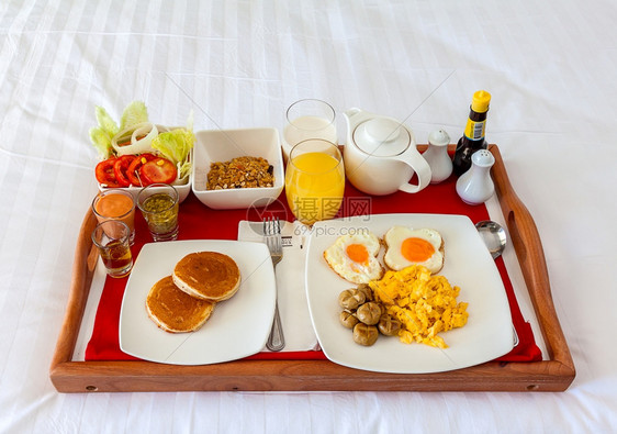 酒店红色的早餐放在床上盘供在旅馆休息的客人用香肠图片