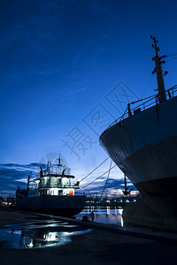 工业的许多渔船和货与许多轮和货在港口靠岸的Silhouette渔船垂直框架面对深蓝紫色双光天空背景出口日落图片