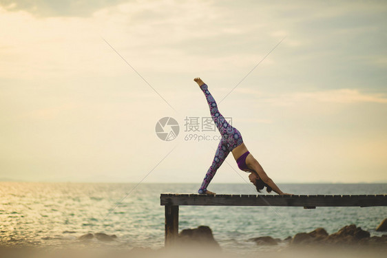 自然健康运动女人在海滩码头做瑜伽姿势晨光照亮图片