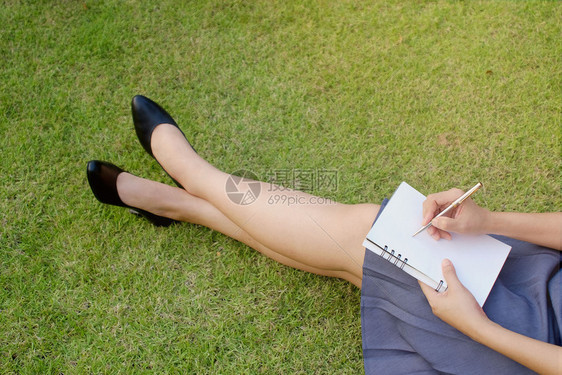 工作妇女手和笔写在户外草地上的笔记本自然杂志闲暇图片