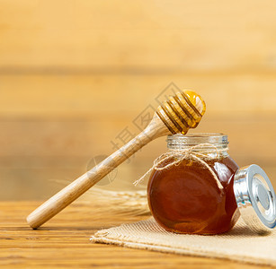 健康蜂蜜和带木棍的梳子罐美味的图片