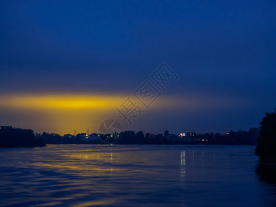 营云荒野夜空的景象和城市灯光的黄色反射从河流和黑暗的天空看到城市灯光的闪亮图片