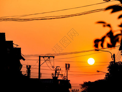 自然橙色天空在太阳周光电线杆树和建筑物后面日落泰国轮廓极图片