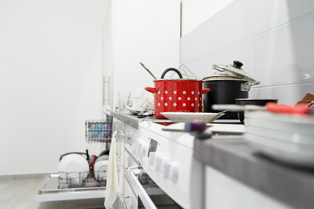 洗碗桩白色厨房的侧边视图在烹饪后一团乱糟的柜台用具和厨房电器上配有未洗过的脏锅和盘子家政图片