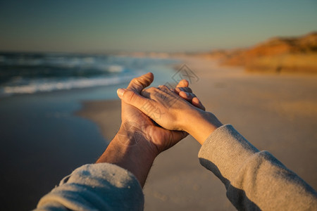 男保持快乐的一对夫妇在沙滩上握着手图片