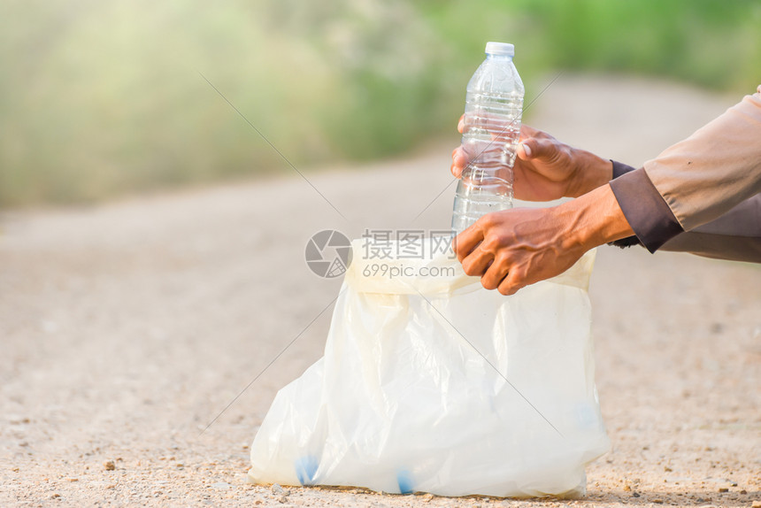 曼诺斯的手正在把塑料瓶捡到垃圾袋里生态概念志愿者采摘自然图片