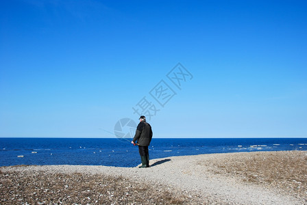 美丽一个男人在蓝海钓鱼从瑞典的西德群岛奥兰来的沙砾海岸上场景风优美图片