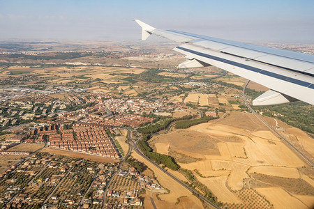 地平线翅膀飞越蓝天和城市风景上空的飞机翼在行时透过机窗口查看年轻的图片