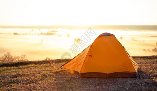 戏剧天空在河上一个山丘的橙色旅游帐篷上面有厚雾清晨夏月风景旅行自由和隐私的概念在河上山头的橙色旅游帐篷上面有浓雾爬坡道图片
