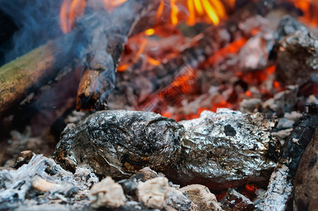在火上烤的土豆在火上用箔纸包着的蔬菜在火上用箔纸包着zegetable在火上烤土豆烹饪热的黄油图片