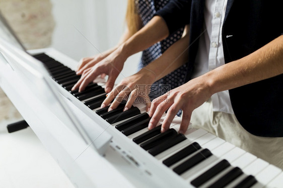 白色的优质人们亲手演奏钢琴键盘的一对夫妇图片